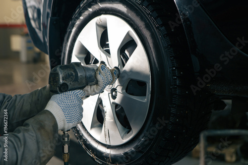 Mechanician changing car wheel in auto repair shop