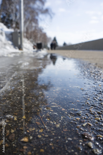 Water flows from the melting snow flowing along the asphalt. Spring melting snow.