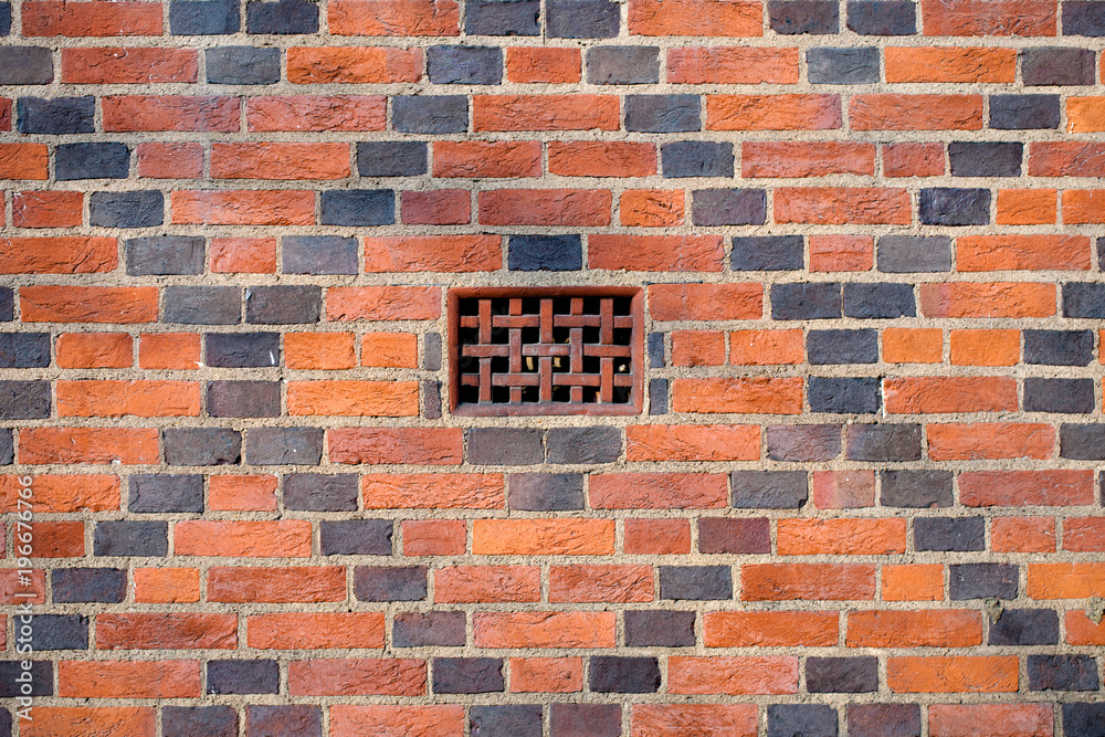 Fototapeta Closeup of red-brick brick wall with gray briks X-lines for background and rusty iron cell in the center