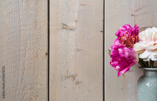 Pink flowers in ceramic vase spring decoration with wood wall background texture 