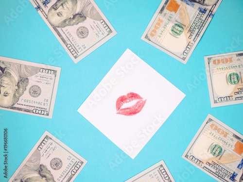 Dollars, white paper with red lips print. Banknotes on a blue background. Love for money. photo