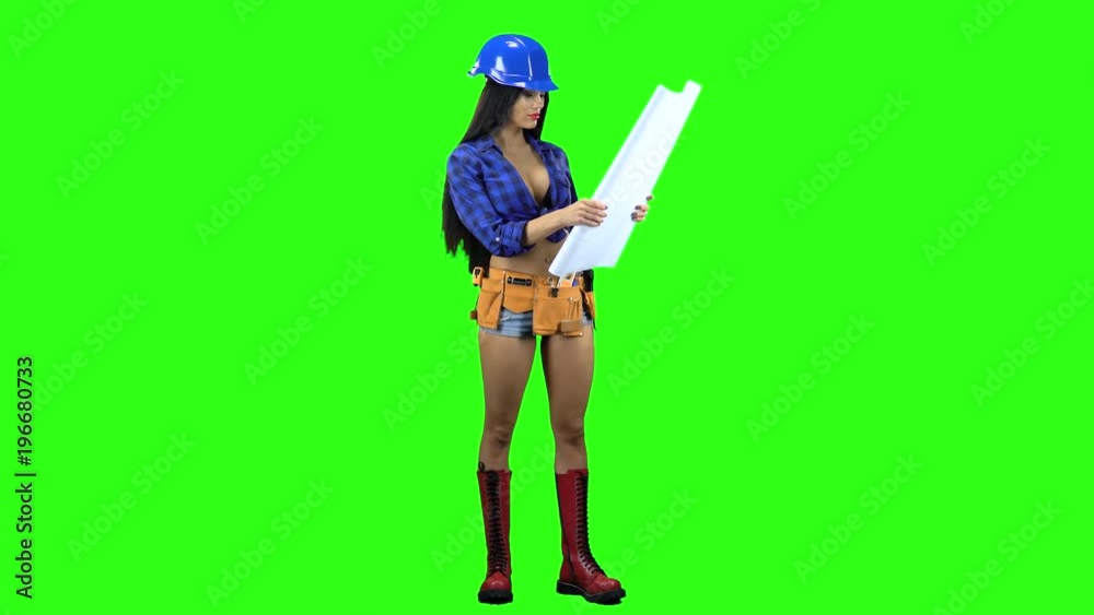 Girl in a helmet and shorts unwraps the paper with a drawing on a green background