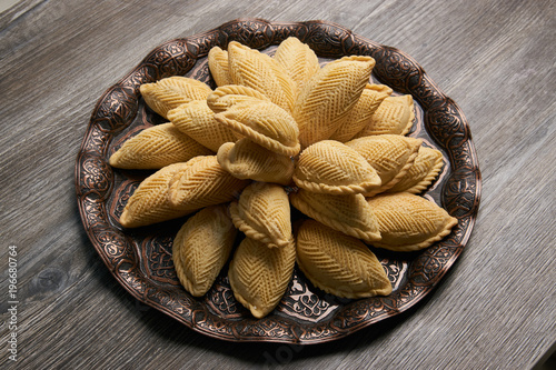 Azerbaijan national pastry Shekerbura with nuts and honey for Novruz holiday on wooden table background