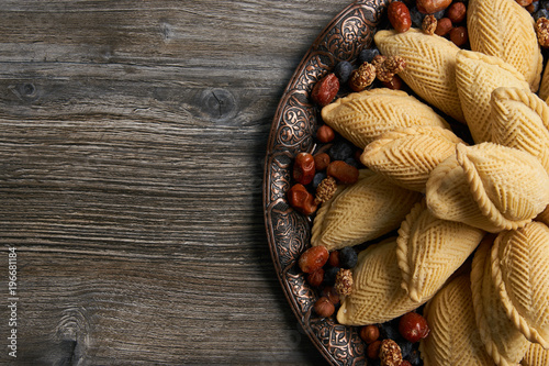 Azerbaijan national pastry Shekerbura with nuts and honey for Novruz holiday on wooden table background