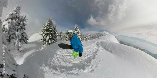 360 OVERCAPTURE 3D: Pro freerider walks up a mountain along trails in deep snow. photo