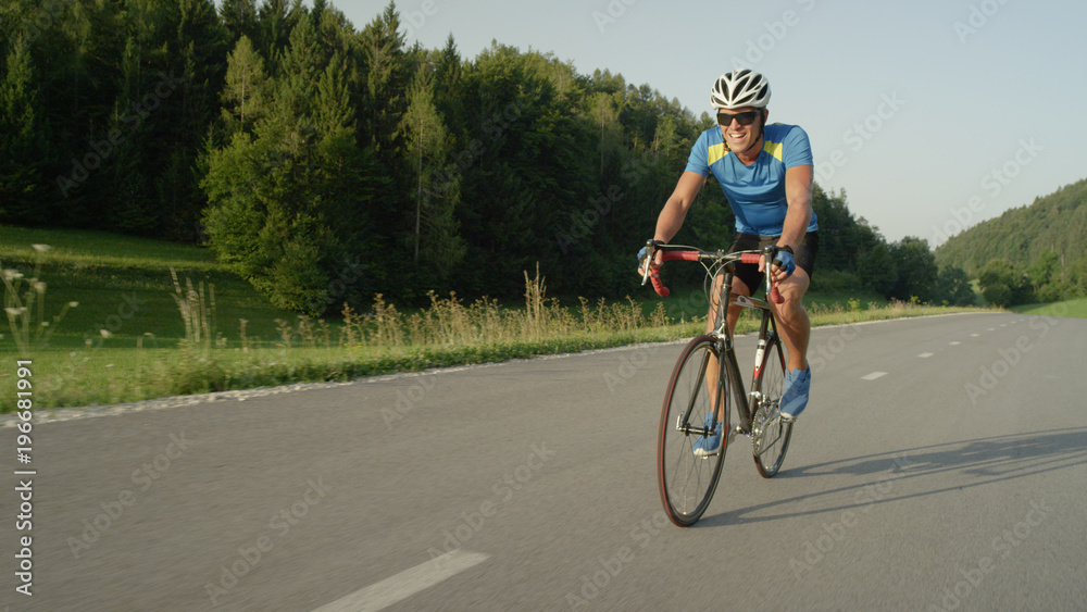 COPY SPACE: Pro biker man riding fast down asphalt road on his road bicycle. COPY SPACE: Pro biker man riding fast down asphalt road on his road bicycle.