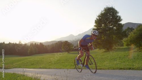 LENS FLARE: Pro rider struggles pedaling uphill during countryside bicycle race.