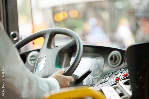 Hands of driver in a modern bus by driving.Concept - close-up of bus driver steering wheel and driving passenger bus photo