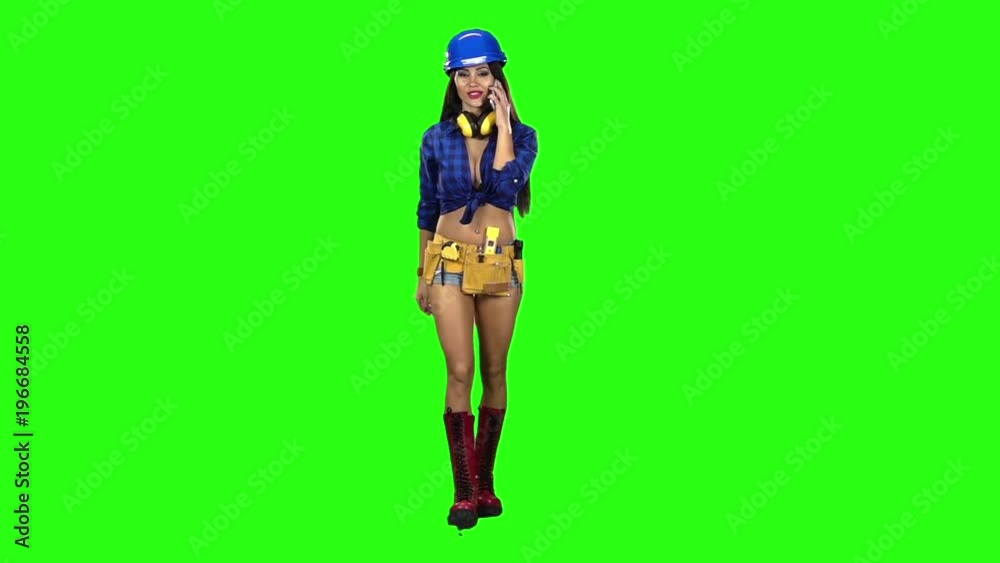 Girl in shorts and a helmet goes is talking on the phone on a green background. Slow motion Girl in shorts and a helmet goes is talking on the phone on a green background. Slow motion