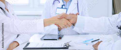 Doctors shaking hands to each other finishing up medical meeting photo