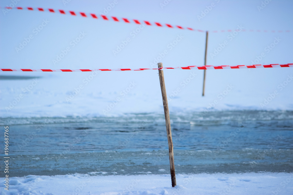 Tape fence on the winter river
