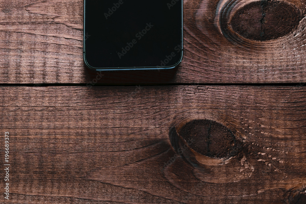 Top view of a modern smartphone with large screen on vintage wooden table. Blank empty display. Mock up Top view of a modern smartphone with large screen on vintage wooden table. Blank empty display. Mock up