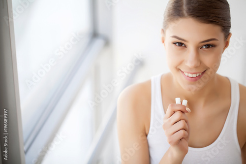 Obraz na plátně Beautiful young woman eating chewing gum, smiling