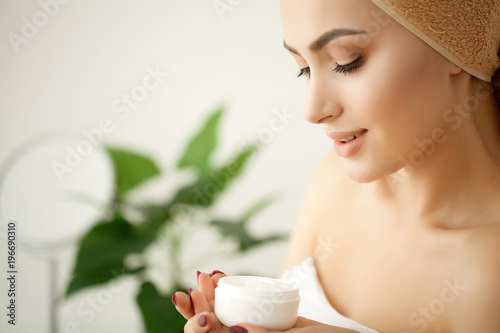 Skin care. Studio shot of beautiful young woman applying moisturizer cream onto her face