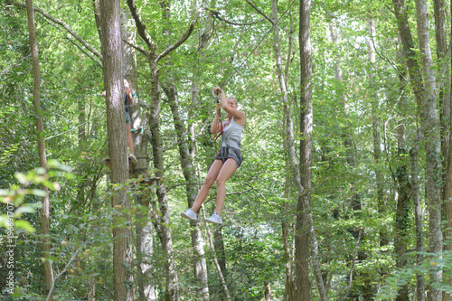 woman suspended on forest adventure course