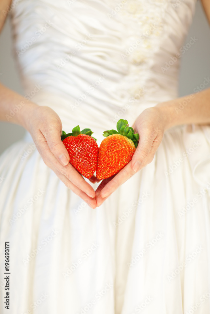 Obraz premium woman bride hands holding some strawberries in her hands, sensual studio shot can be used as background