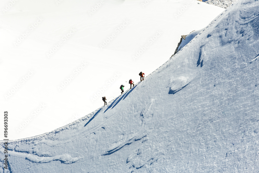 Mont Blanc mountaneers walking on snowy ridge.