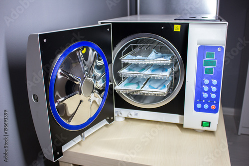Sterilizing medical instruments in autoclave, Tongs for manicure on the background of a medical autoclave photo