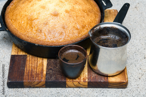 home-made pie in a frying pan and coffee on a wooden dinette photo