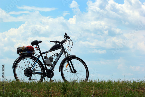 Motorized bicycle on green grass against blue sky background
