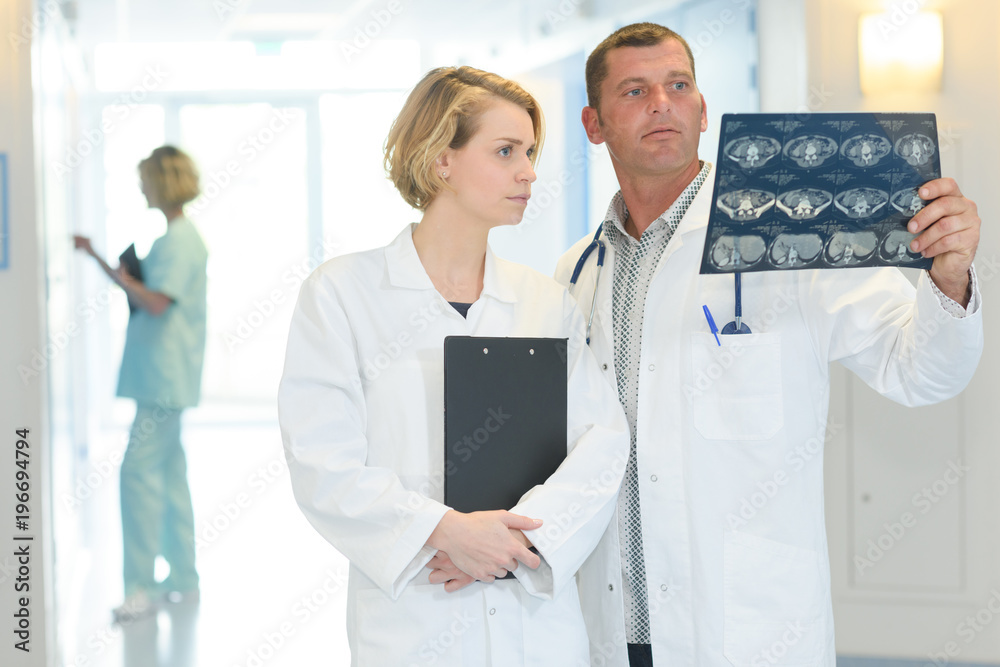 2 doctors are looking at patient xray in hospital corridor 2 doctors are looking at patient xray in hospital corridor