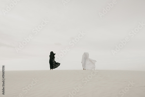 Black vs White contrast concept of two humans draped in fabric in the desert
