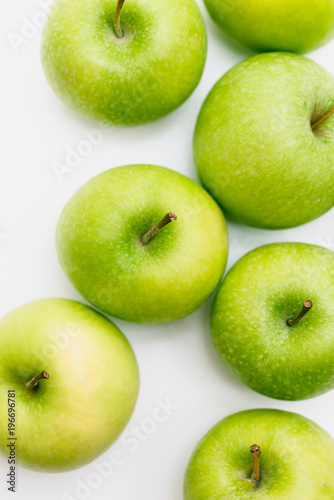Flatlay with seven fresh, green-yellow Golden Smith or Granny Smith apples on white background