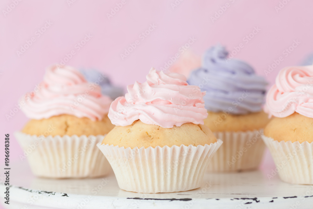 Cupcakes with pink and violet buttercream standing on pastel pink background. Cupcakes with pink and violet buttercream standing on pastel pink background.