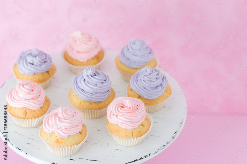 Cupcakes with pink and violet buttercream standing on pastel pink background.
