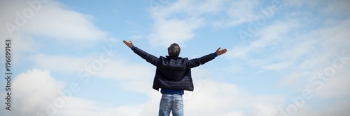 Composite image of rear view of a man raising his arms up