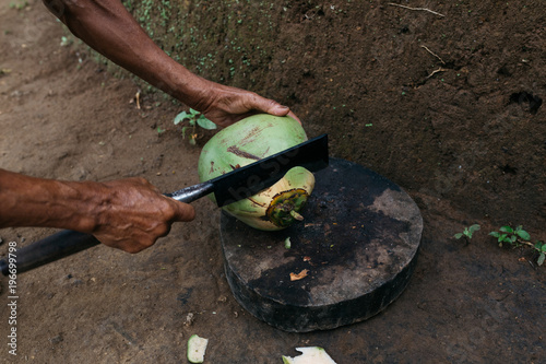 anonymous male chopping coconut with big blade photo