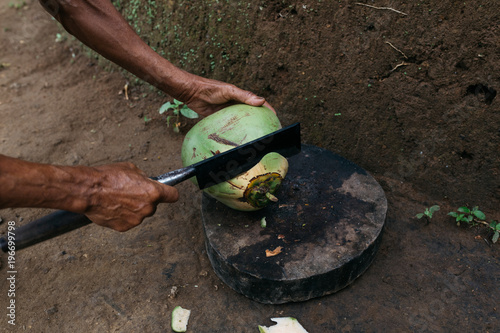 anonymous male chopping coconut with big blade