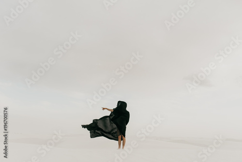 Dark mysterious black cloth blowing in the wind in the desolate desert hiding a human silhouette photo