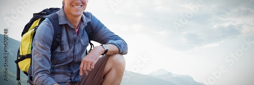 Composite image of portrait of confident male hiker crouching