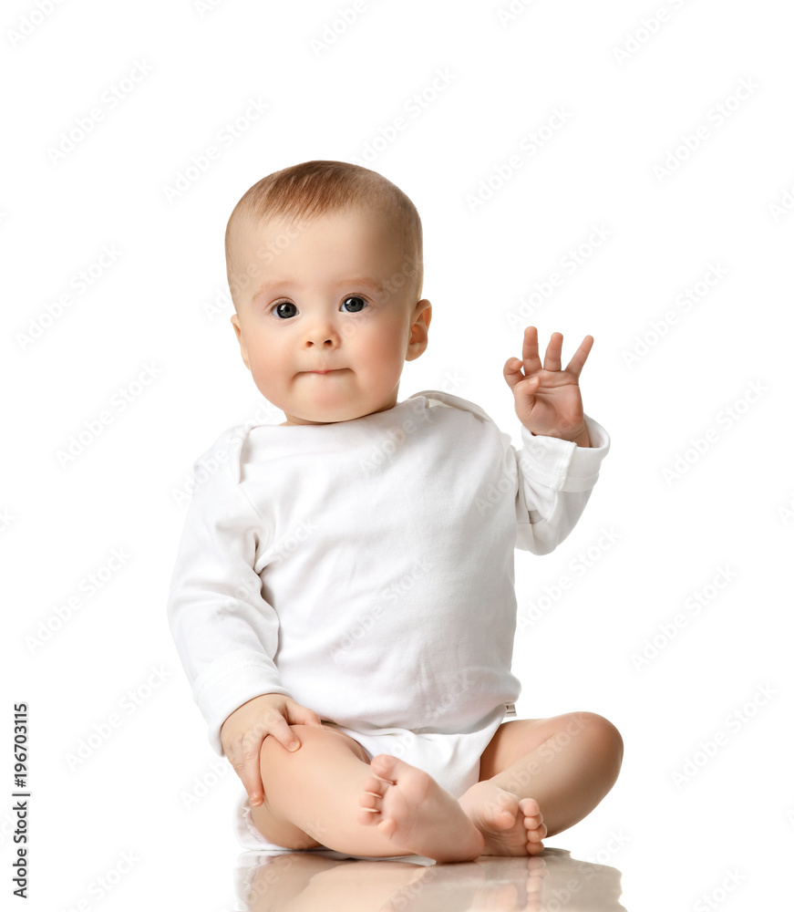 7 month infant child baby girl toddler sitting in white shirt with hand up show ok sign 7 month infant child baby girl toddler sitting in white shirt with hand up show ok sign