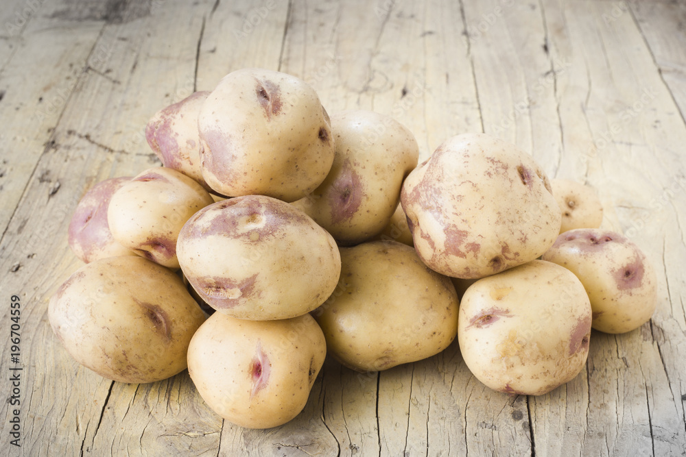 approach to pile of potatoes on wooden table approach to pile of potatoes on wooden table