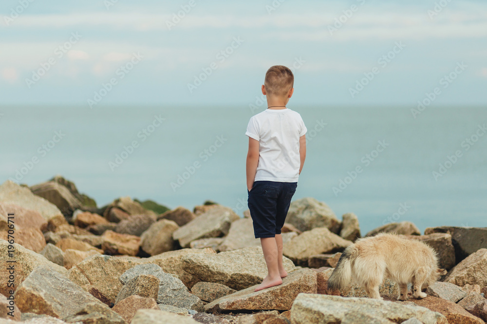 Little boy standing alone and looking at the beautiful sea