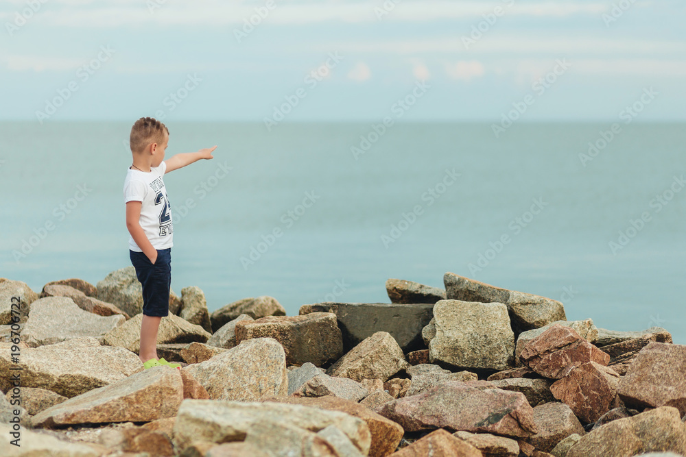 Funny little kid pointing finger far to sea