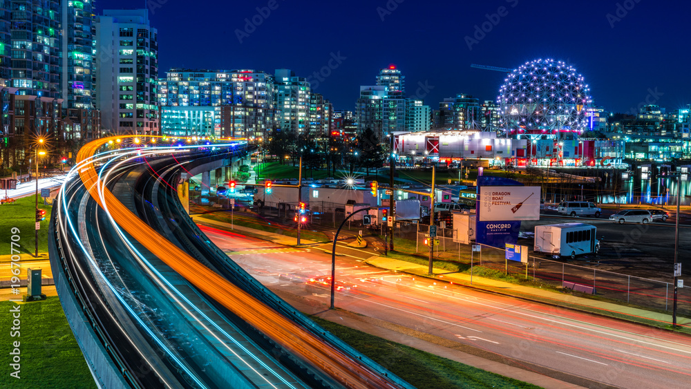 Fototapeta premium Długa ekspozycja centrum Vancouver, Kolumbia Brytyjska, Kanada. Jedno z najbardziej tętniących życiem miast Ameryki Północnej. Szlak świateł pociągów podniebnych, gwiazdy i błyszczy.