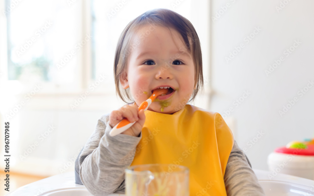 Happy little baby boy eating food in his house Happy little baby boy eating food in his house