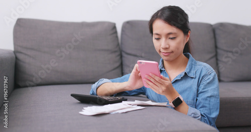 Housewife using cellphone to take photo on receipt and calculate the expenditure of daily life