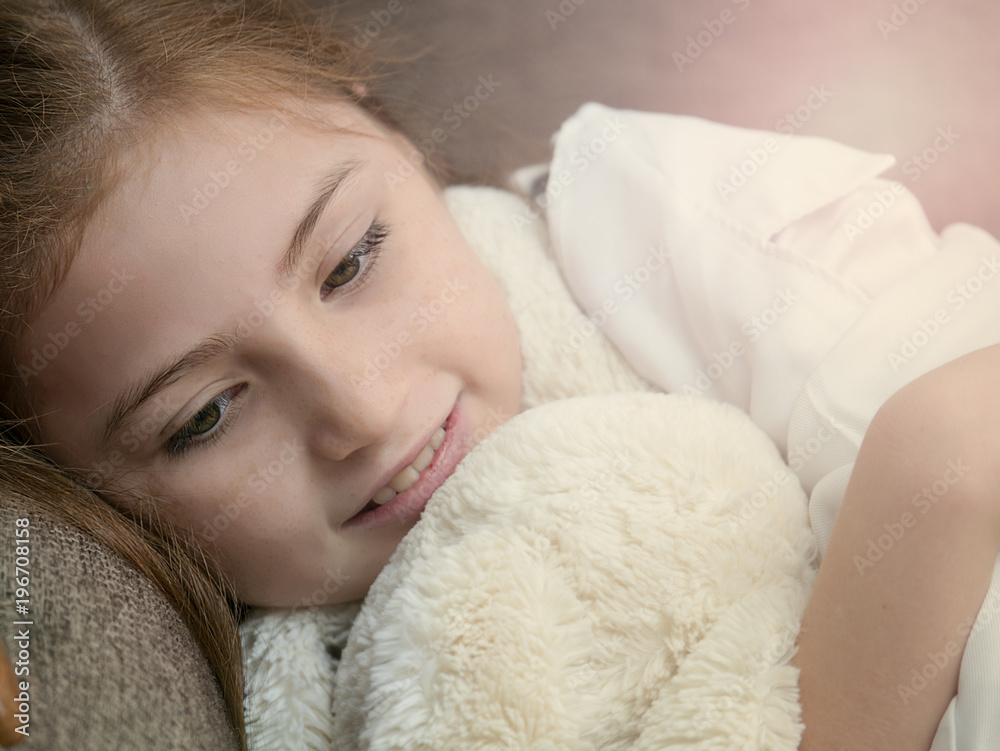 Cute caucasian blonde girl kid laying on sofa with doll feeling happy Cute caucasian blonde girl kid laying on sofa with doll feeling happy