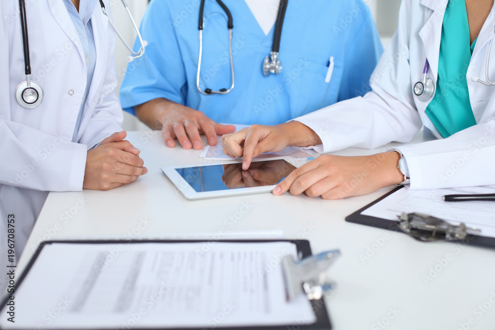 Group of doctors at medical meeting. Close up of physician using touch pad or tablet computer Group of doctors at medical meeting. Close up of physician using touch pad or tablet computer