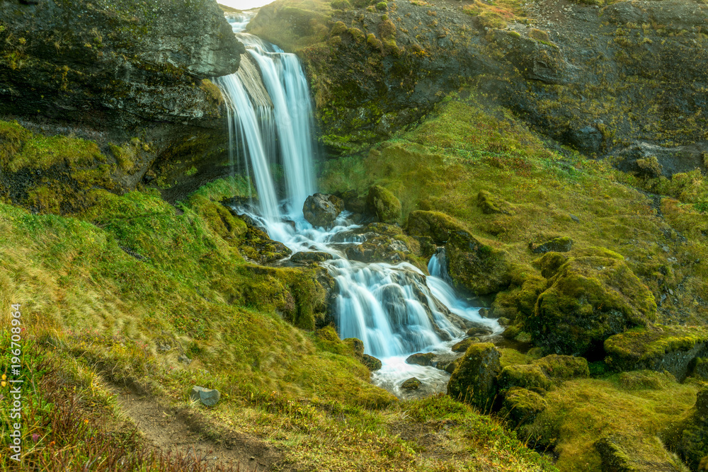 Long exposure of a small waterfall running through a green moss valley in Iceland