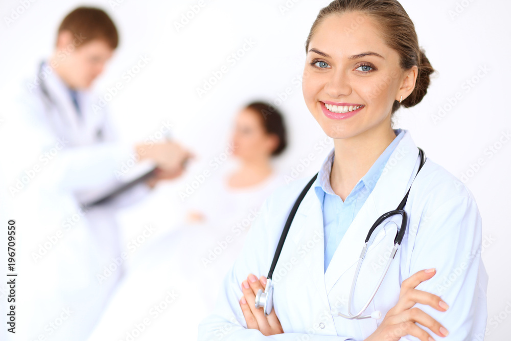 Cheerful smiling female doctor on the background with physician and his patient in the bed Cheerful smiling female doctor on the background with physician and his patient in the bed
