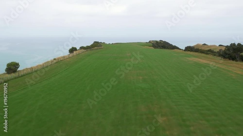 Drone fly over of a golfer swinging on a cliffside golf course off the coast of New Zealand.