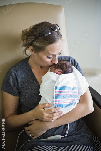 Mother kissing her newborn premature baby in the hospital