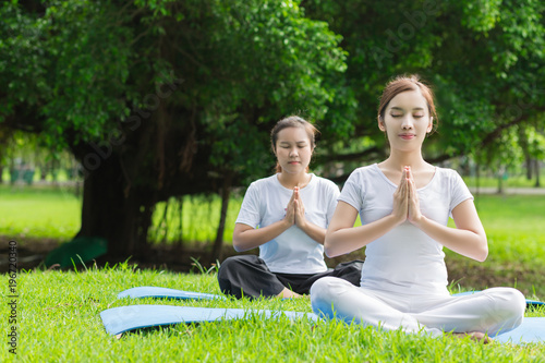 Two  Asian woman practicing yoga  at the Green park ,  Healthy lifestyle Concept.