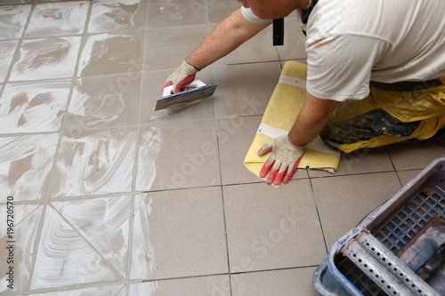 Grouting ceramic tiles on the floor by a man. photo