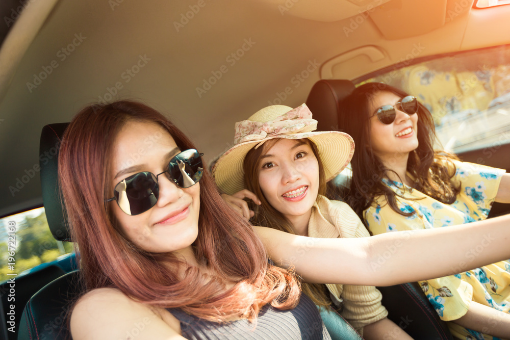 Enjoying woman with her girlfriend   in red car summer vacation, holidays, travel, road trip and people concept .